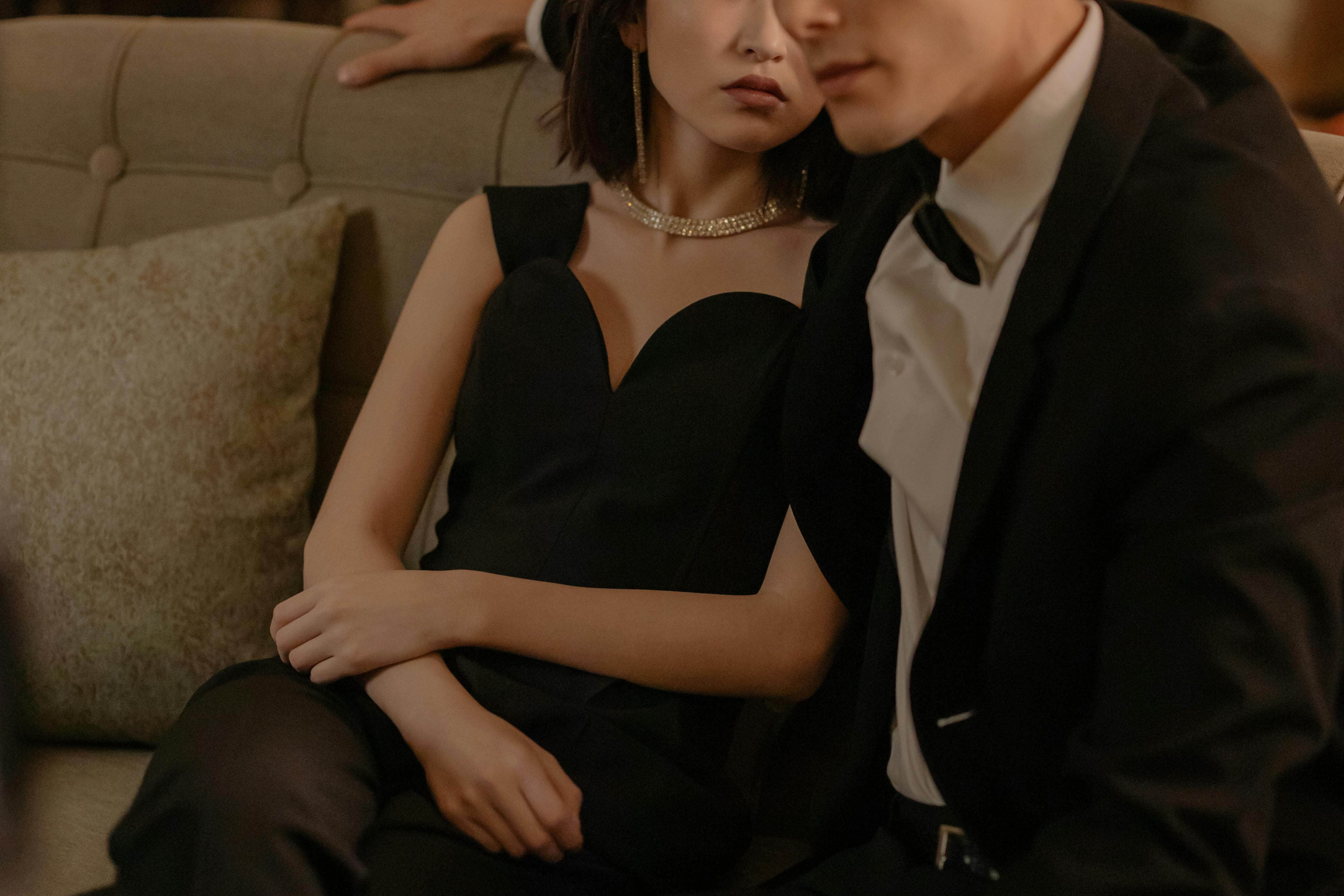 a high class escort in an elegant black dress wtih a client in a suit