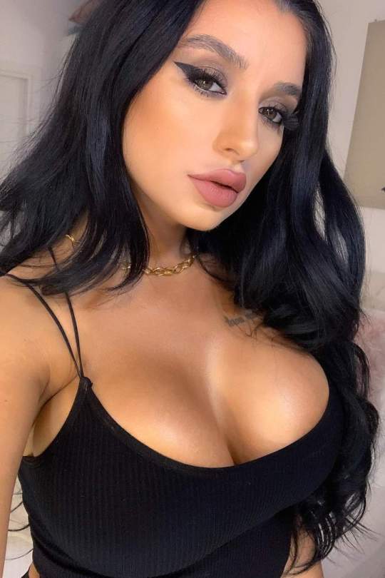 Elissa taking a selfie with a black top on, showing off her breasts. 